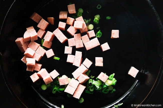 Stir-frying Spam and green onion in a skillet.