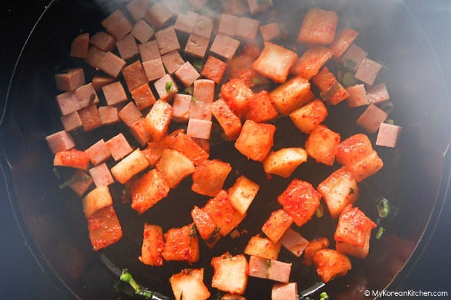 Stir-frying kimchi and Spam in a skillet.