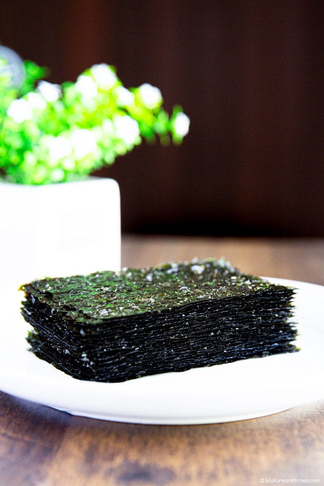 Roasted seaweed placed on a white plate on wooden benchtop.