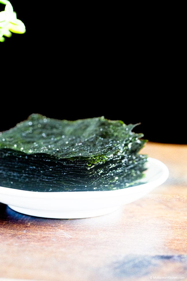 Roasted seaweed placed on a white plate on wooden benchtop.