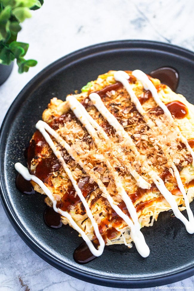 Close up photo of cabbage omelette served on a black plate, white backdrop.