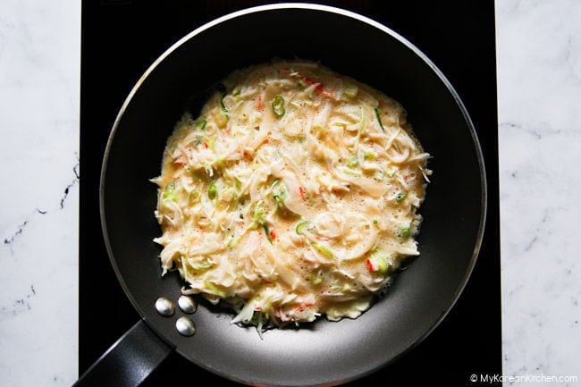 Pan frying cabbage and egg omelette.