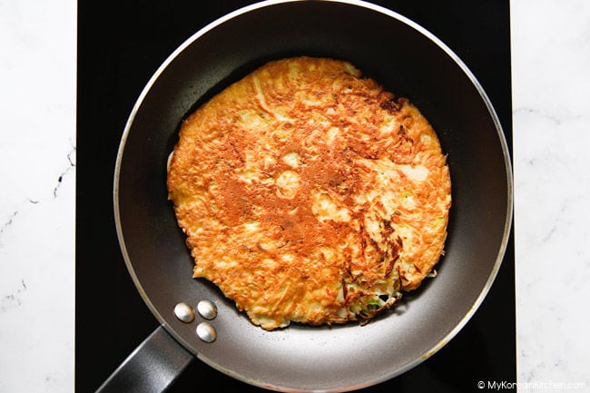 Browned cabbage and egg omelette in a frying pan.