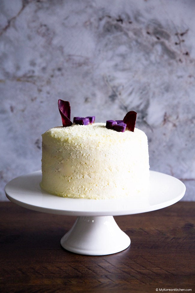 Front shot of a Korean sweet potato cake on a white cake stand.