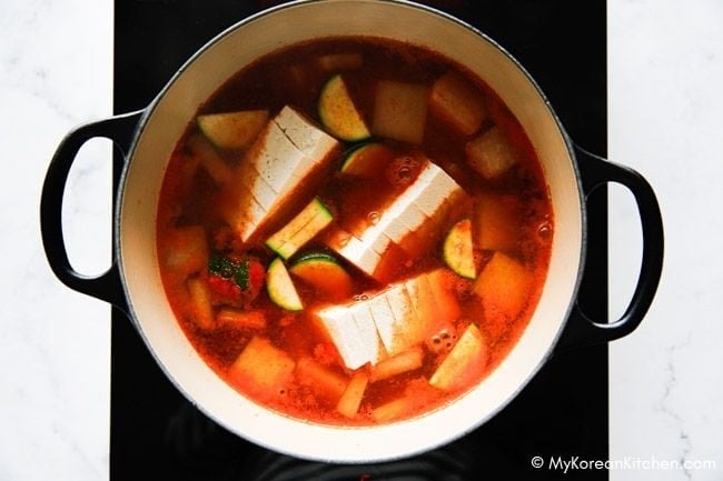 A pot of soup with tofu and mixed vegetables simmering in broth.