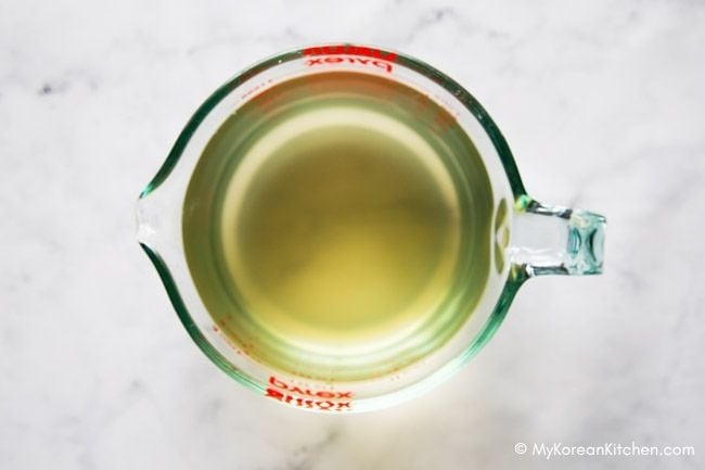 A glass measuring cup filled with Korean soup stock.