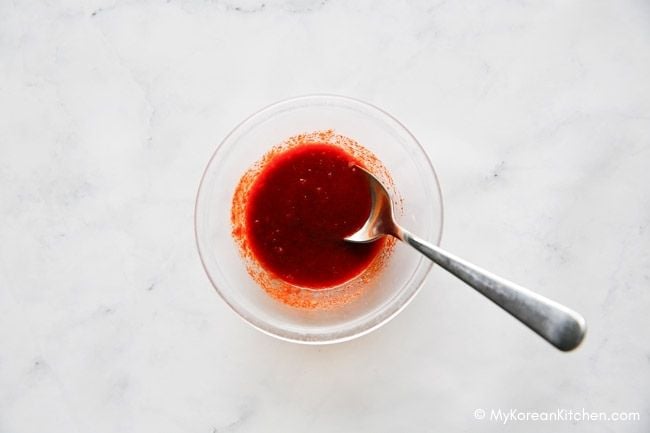 A spoon is in a bowl of sauce.