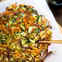 Holding a piece of crispy Korean zucchini pancake with chopsticks