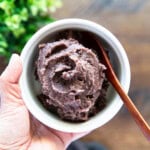 Holding a bowl of sweet red bean paste with a wooden spoon inside.