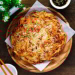 Crispy potato pancake served on a wooden plate with dipping sauce on the right-hand side.