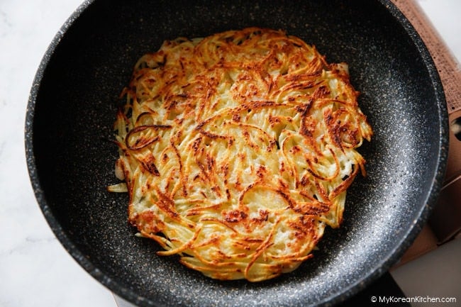 Golden potato pancake in a nonstick pan.
