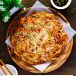 Crispy potato pancake served on a wooden plate with dipping sauce on the right-hand side.