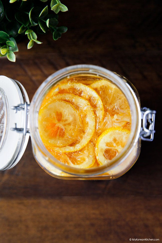 Top-down image of lemon syrup with sliced lemons visible from above, in a jar placed on a wooden board.