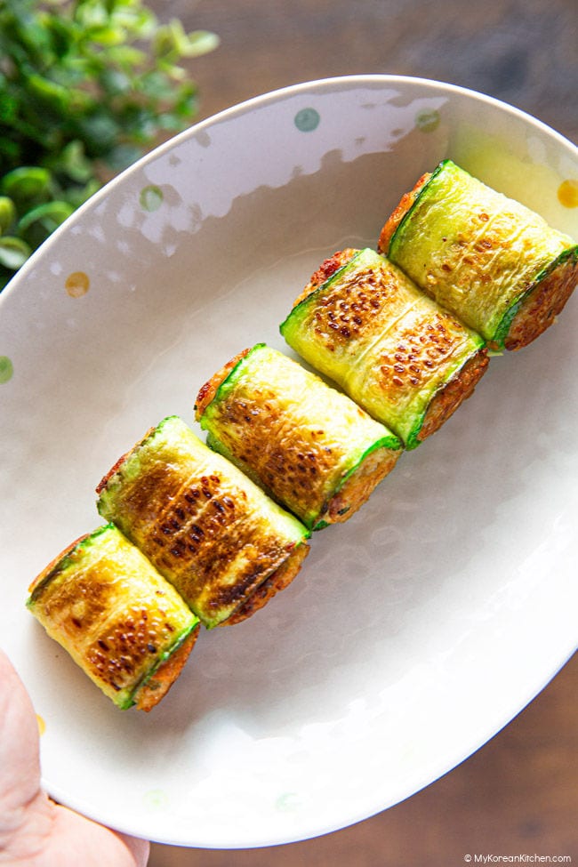 Holding a plate of korean zucchini rolls hobak mari