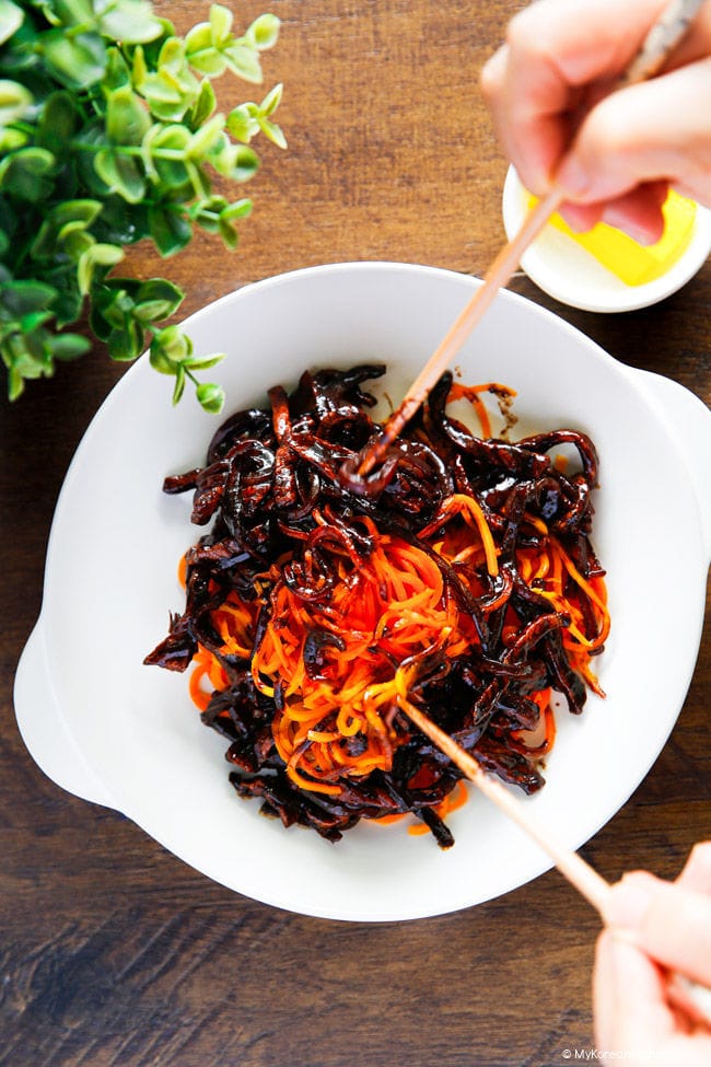 Mixing jajang sauce with carrot noodles using chopsticks