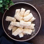 Small piece of injeolmi Korean rice cake on a wooden plate over a wooden board background