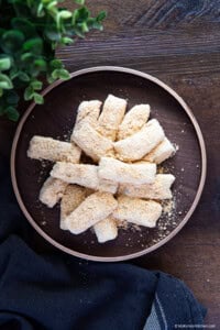 Small piece of injeolmi Korean rice cake on a wooden plate over a wooden board background