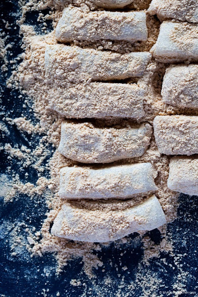 Injeolmi Korean rice cakes lined up on a baking tray generously dusted with roasted soybean powder