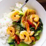 holding a spoonful of rice topped with bok choy and shrimp