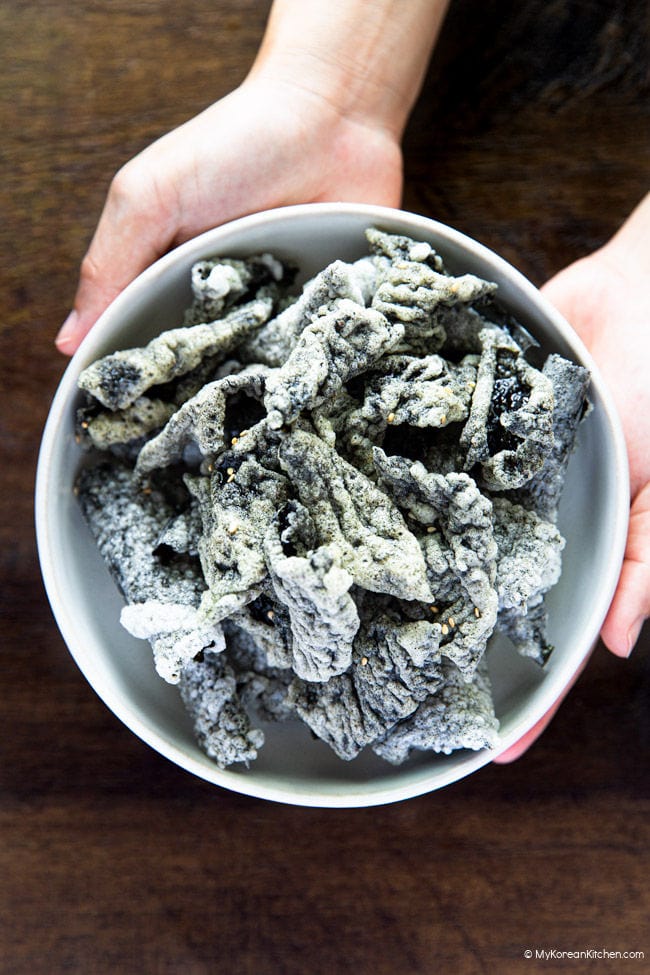Hands holding a bowl of Korean seaweed chips