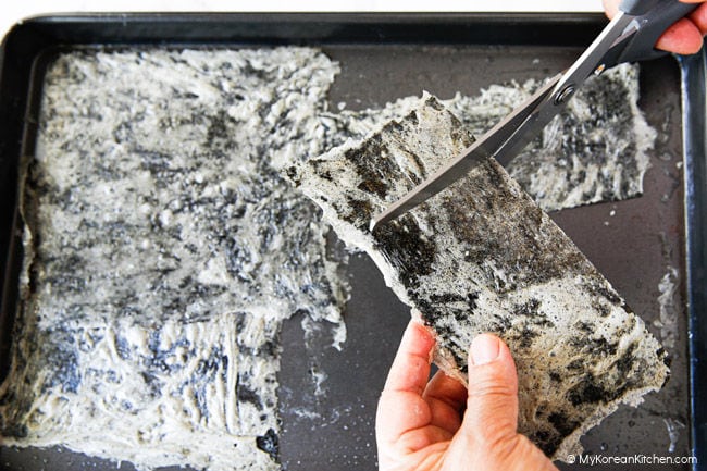 Cutting dried seaweed into pieces with scissors.