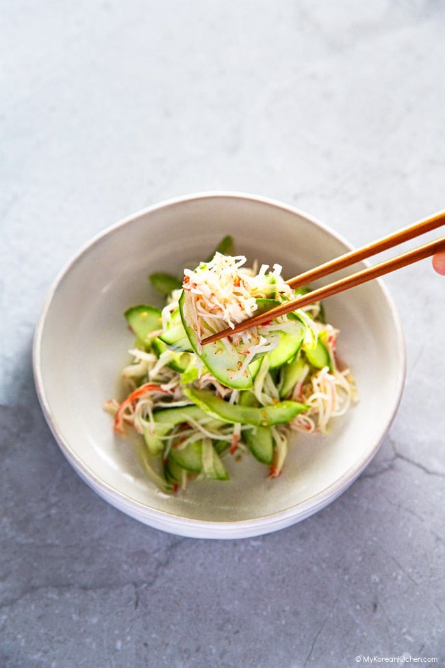 holding Korean cucumber crab salad with a pair of chopsticks
