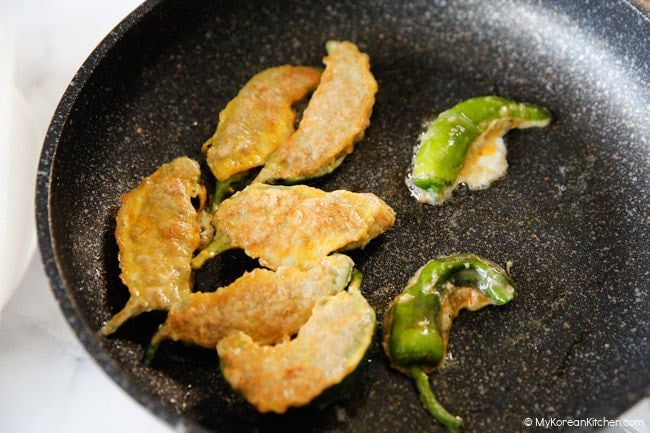 Pan-frying gochujeon in a frying pan until golden brown.