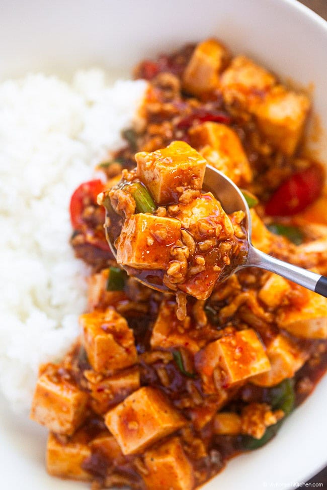 A spoonful of Korean mapo tofu with soft tofu, ground pork, and rich spicy sauce over steamed rice