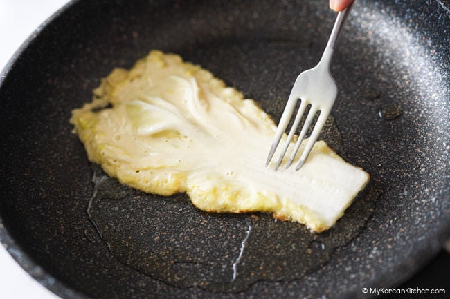 Napa cabbage pancake cooking in a frying pan.