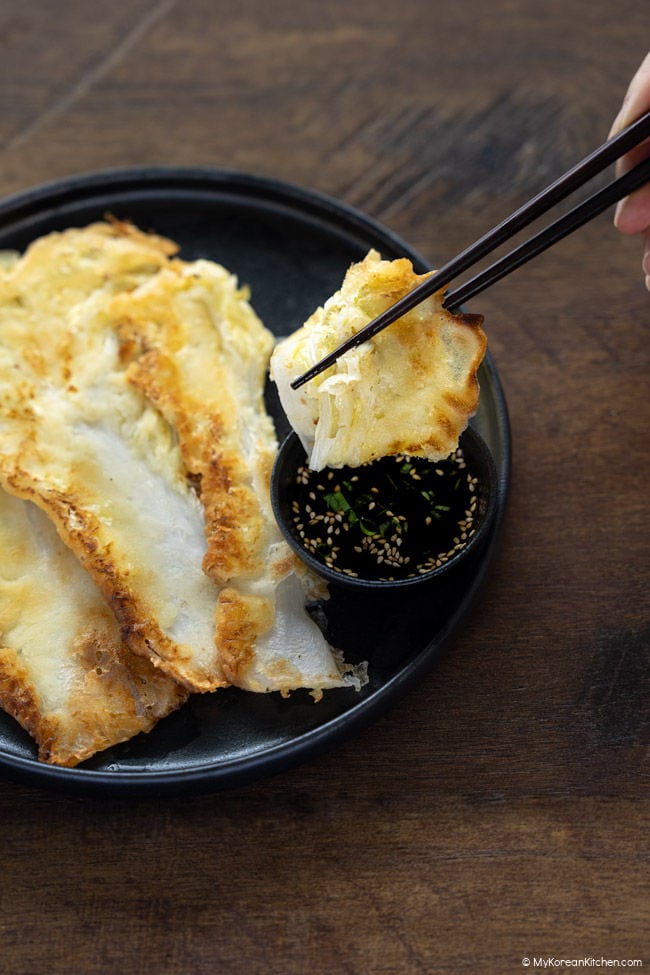 A piece of baechujeon being held with chopsticks.