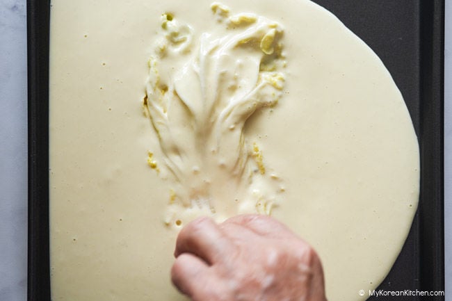Napa cabbage leaf being coated evenly in pancake batter.