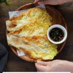 Holding a wooden plate of Korean cabbage pancakes.