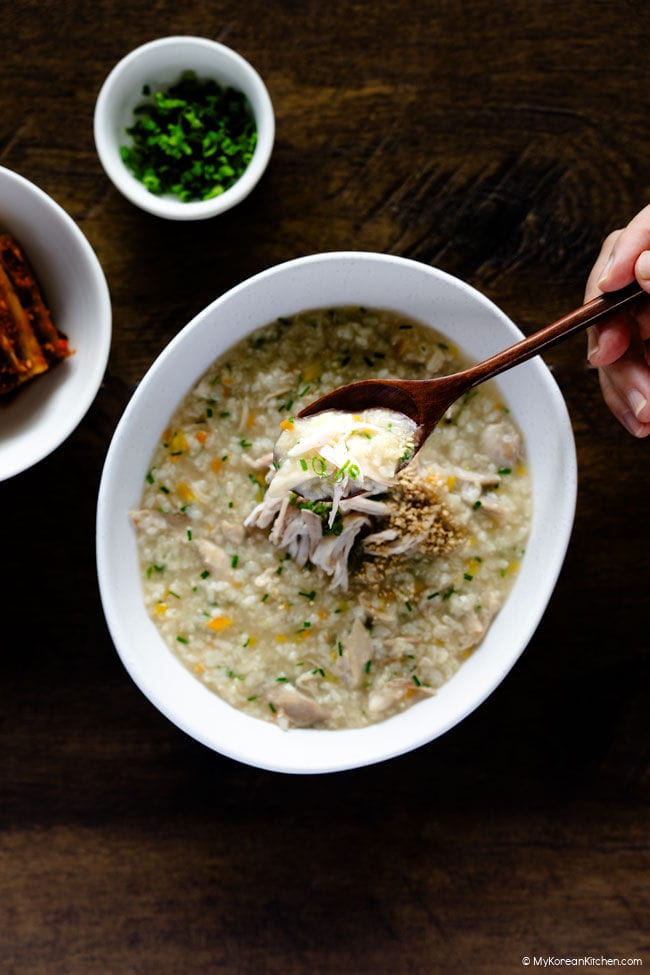 Holding a wooden spoon filled with dakjuk, Korean chicken porridge
