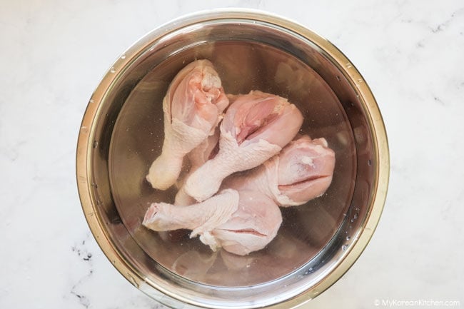 Chicken drumsticks soaking in a mixture of water and vinegar in a bowl