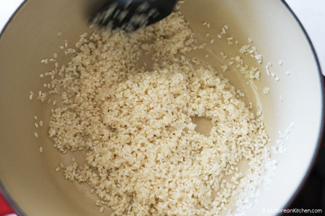 Glutinous rice and short-grain rice being stir-fried briefly in sesame oil