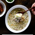 Holding a wooden spoon filled with dakjuk, Korean chicken porridge