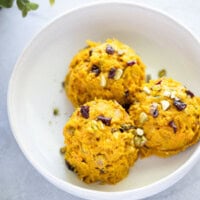 Three scoops of creamy Korean pumpkin salad with chopped nuts and dried berries, served in a white bowl.