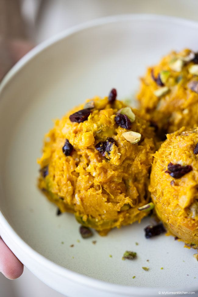 Close-up of Korean pumpkin salad showing its chunky, creamy texture with visible chopped nuts and dried berries.